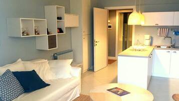 Un saló modern amb un sofà, una taula de centre i una cuina amb taula de dinar.