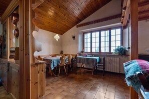 Un intérieur rustique en bois, avec un coin repas, un plafond en bois et de grandes fenêtres.