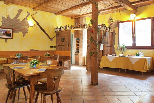 A restaurant with wooden tables and chairs, a brick wall, and a window with natural light.