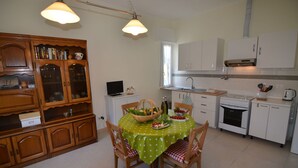 Una cocina con armarios de madera, una mesa de comedor con mantel verde y una estufa.