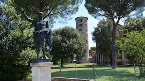 Una estatua en un parque, con una torre al fondo.