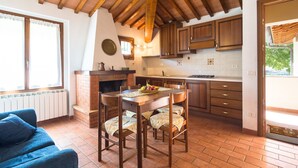 A cozy kitchen with wooden beams, a dining table, and a blue sofa.
