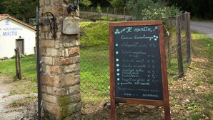 A rustic stone building with a signboard listing menu items and prices.