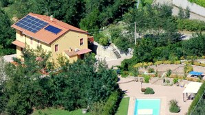 Una casa con techo de paneles solares, piscina y jardín.