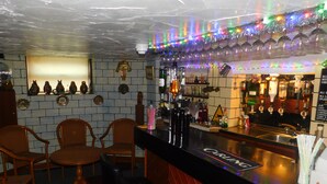 A bar area with a black countertop, multiple bottles, and glasses. There are wooden chairs and a small table. - The Gynway (Blackpool)