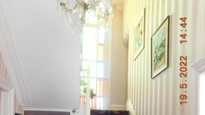 A staircase with patterned carpet, a chandelier, and framed artwork on the walls. - The Gynway (Blackpool)