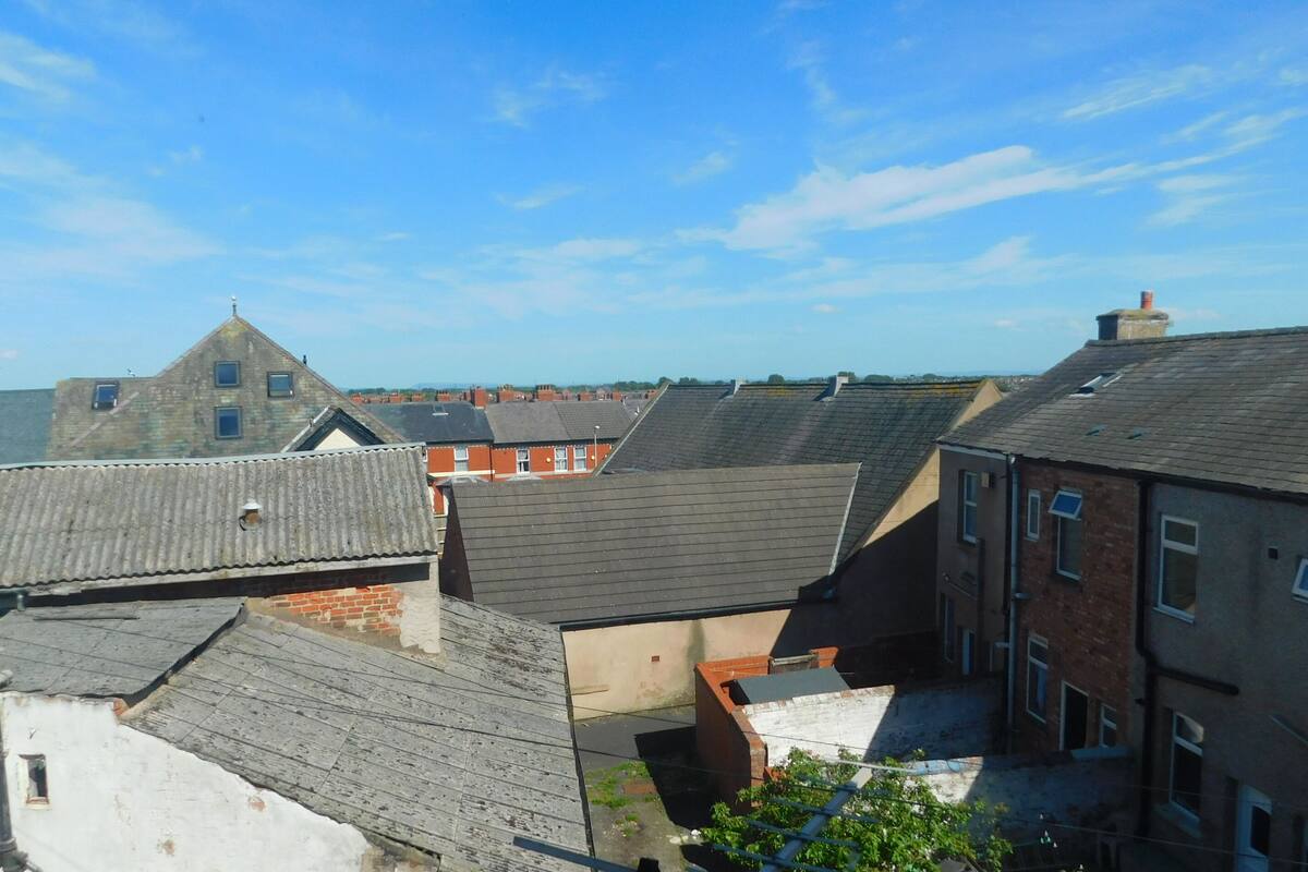 A view of residential buildings with sloped roofs and brick facades, likely in a hilly or coastal area.