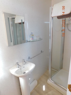 Un baño con lavamanos blanco, espejo y cabina de ducha de vidrio.