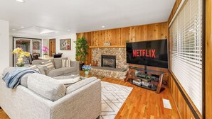 Ein modernes Wohnzimmer mit Kamin aus Stein, einem großen Flachbildfernseher und einer gemütlichen Sitzecke.