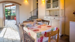 A dining area with a table set for four, a staircase, and a cabinet with glass doors. - Belvilla by OYO Gallorimpi (Dicomano)