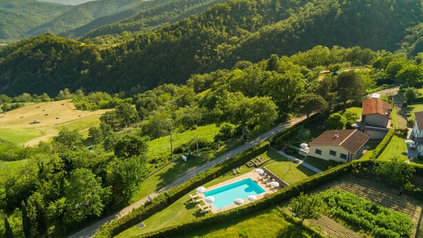 A residential area with a swimming pool, surrounded by lush greenery and hills in the background. - Belvilla by OYO Gallorimpi (Dicomano)