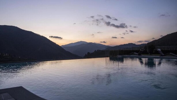 A serene pool area with a mountain backdrop, reflecting the sky and clouds.