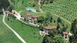 An aerial view of a rural property with stone buildings, a swimming pool, and terraced fields.