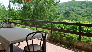 An outdoor patio with a table and chairs, overlooking a lush green valley.