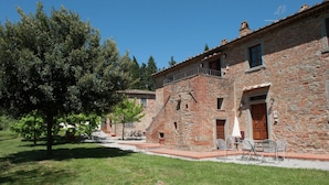 A stone building with a balcony, outdoor seating, and a tree in the foreground. - Belvilla by OYO Tiglio (Cortona)