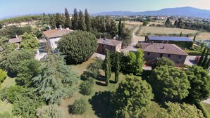 An aerial view of a rural property with multiple buildings, surrounded by trees and open fields. - Belvilla by OYO Leccio (Cortona)