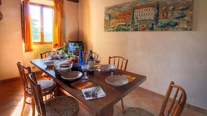 A dining table set with plates, glasses, and a bottle, surrounded by wooden chairs. - Belvilla by OYO Lunghe (Siena)