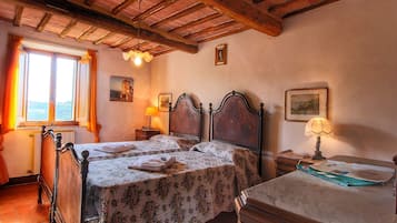 A room with two wooden beds, a wooden dresser, a window with curtains, and a lamp on a nightstand.