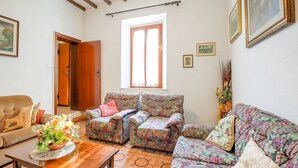 Un accogliente soggiorno con divani a motivi floreali, un tavolino in legno e una grande finestra.