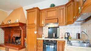Una cucina con mobili in legno, un camino in mattoni, un fornello e un lavello.