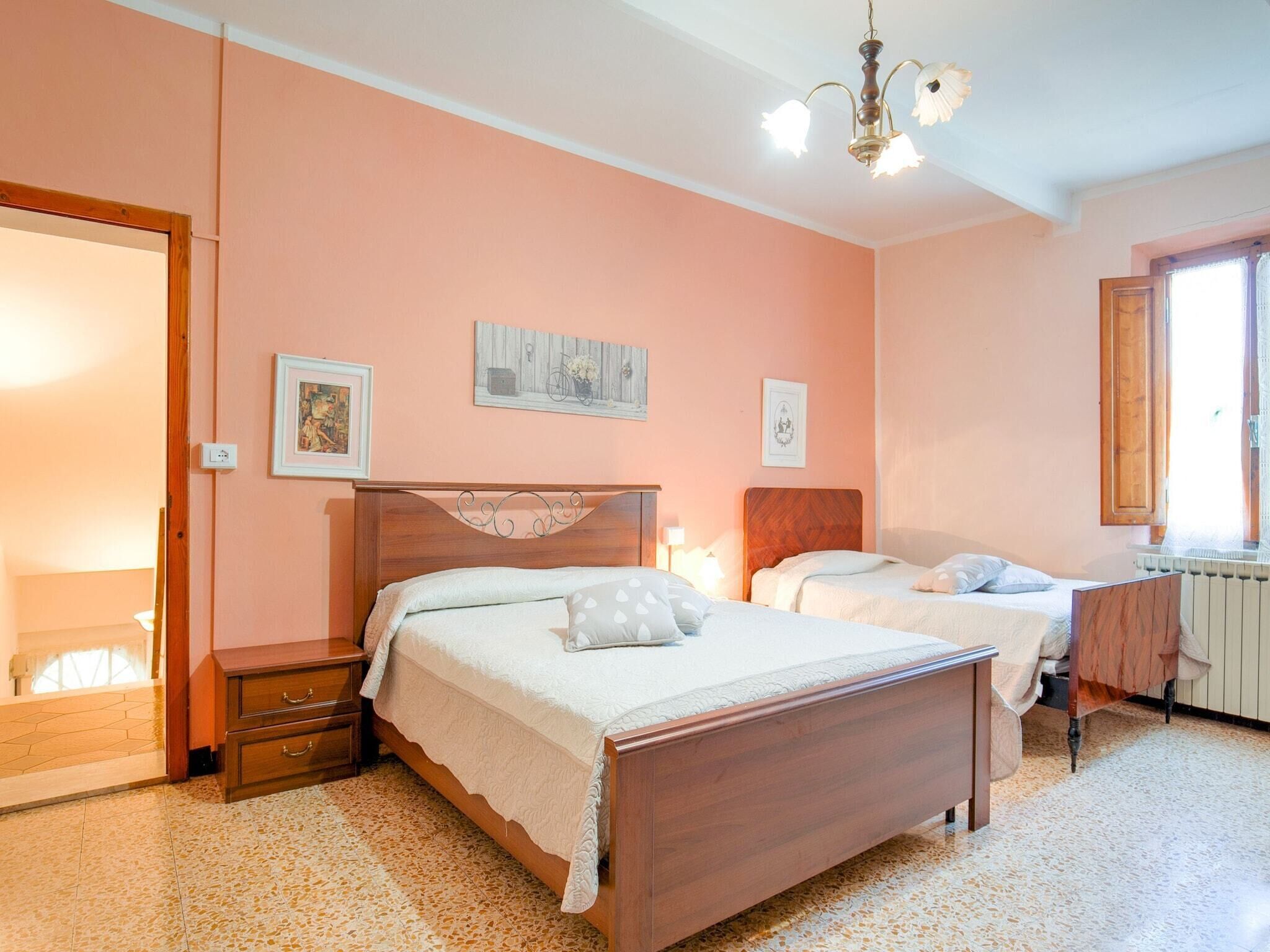 A bedroom with two beds, a wooden headboard, a nightstand, a dresser, and a radiator.