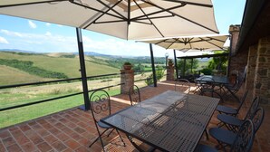 A terrace with a table and chairs, a brick floor, and a view of the countryside. - Belvilla by OYO Gatterino (Peccioli)