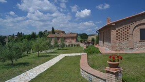 A brick building with a stone pathway leading to a garden area with potted plants. - Belvilla by OYO Gatterino (Peccioli)