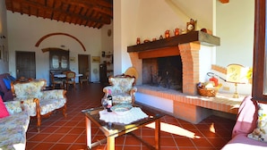 Un soggiorno con camino, due poltrone floreali, un tavolino da caffè e una zona pranzo con tavolo e sedie.