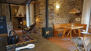 Una habitación acogedora con pared de piedra, chimenea, mesa de madera y un banco.