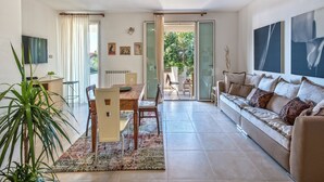 Ein modernes Wohnzimmer mit Essbereich, einer Couch, einem Fernseher und Blick ins Freie.