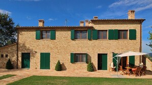 A two-story stone building with green shutters, a brick patio, and outdoor seating. - Cottage in Montelabbate with Pool & Forest (Montelabbate)
