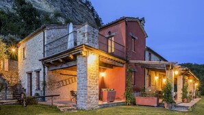 A stone house with a balcony and a covered patio area.
