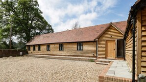 A wooden building with a tiled roof and a gravel driveway. - The Old Dairy (Wokingham)