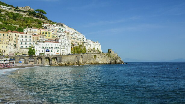 Un pueblo costero con edificios de colores, una playa y un muro marítimo.