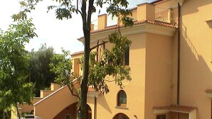 A building with a beige facade, multiple windows, and a wooden fence.