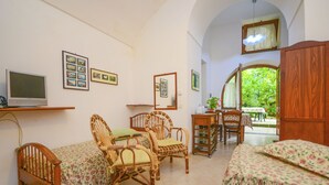 A cozy room with a bed, two chairs, a small table, and a TV.