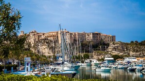 A marina with boats docked, a building with multiple stories in the background, and a clear blue sky. - Belvilla by OYO Nicolֳ² (Ricadi)