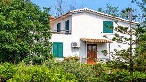 A white building with green shutters, a tiled roof, and an air conditioning unit. - Belvilla by OYO Nicolֳ² (Ricadi)