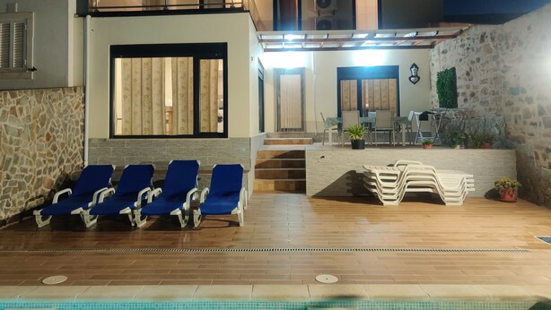 A modern villa with a pool, blue lounge chairs, and a dining area with outdoor seating. - Vacation home in Baixo Alentejo, with swimming pool and barbecue, half an hour from the Algarve (Santa Clara-a-Nova, Almodôvar)