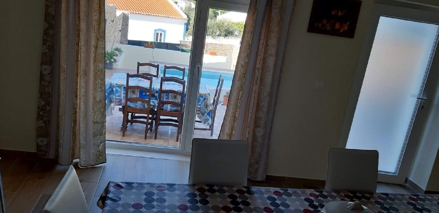 Een kamer met uitzicht op een zwembad en terras.