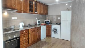 A modern kitchen with wooden cabinets, a built-in oven, a washing machine, and a refrigerator. - Vacation home in Baixo Alentejo, with swimming pool and barbecue, half an hour from the Algarve (Santa Clara-a-Nova, Almodôvar)