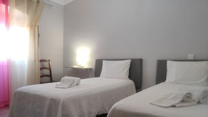 A hotel room with two beds, each with a white bedspread and pillows, a bedside table with a lamp, and a chair. - Vacation home in Baixo Alentejo, with swimming pool and barbecue, half an hour from the Algarve (Santa Clara-a-Nova, Almodôvar)