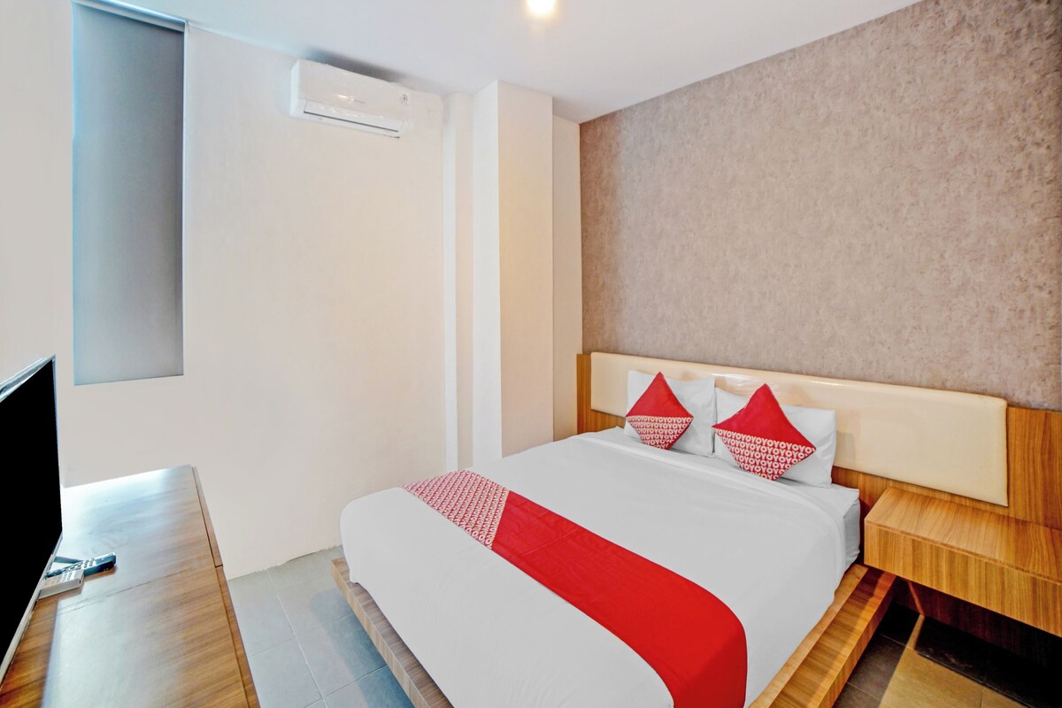 Una camera d'albergo moderna con un letto grande, una TV e un condizionatore d'aria integrato.