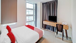 A hotel room with a bed, a desk with a chair, a television, and a window with curtains. - OYO 90559 Gamacity Residence (Medan)