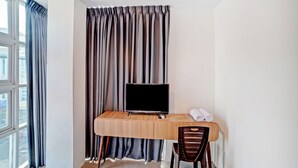 A modern hotel room with a wooden desk, a television, and a chair. - OYO 90559 Gamacity Residence (Medan)