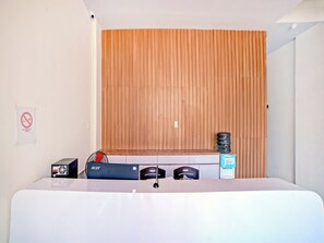 Una camera d'albergo con un letto, una parete in listelli di legno, un cartello che indica il divieto di fumare, un distributore d'acqua e una ciabatta multipresa.