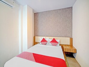 Una camera d'albergo con un letto, un comodino in legno e una testiera con una parete strutturata sullo sfondo.