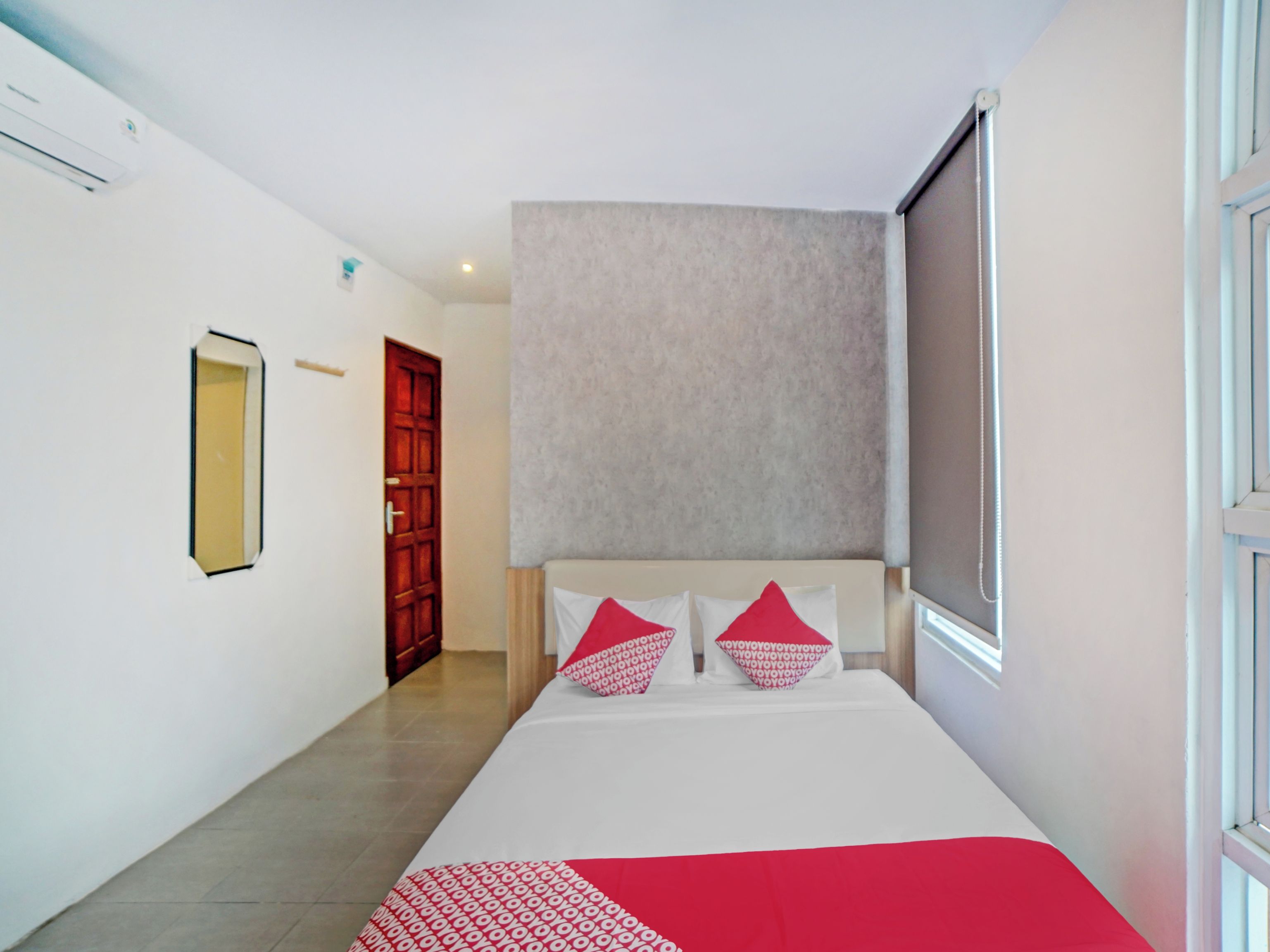 A hotel room with a bed, a door, and a window.
