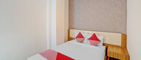A hotel room with a bed, a nightstand, a wall-mounted air conditioner, and a textured wall.