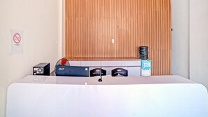 A hotel room with a bed, a wooden slat wall, a no-smoking sign, a water dispenser, and a power strip. - OYO 90559 Gamacity Residence (Medan)